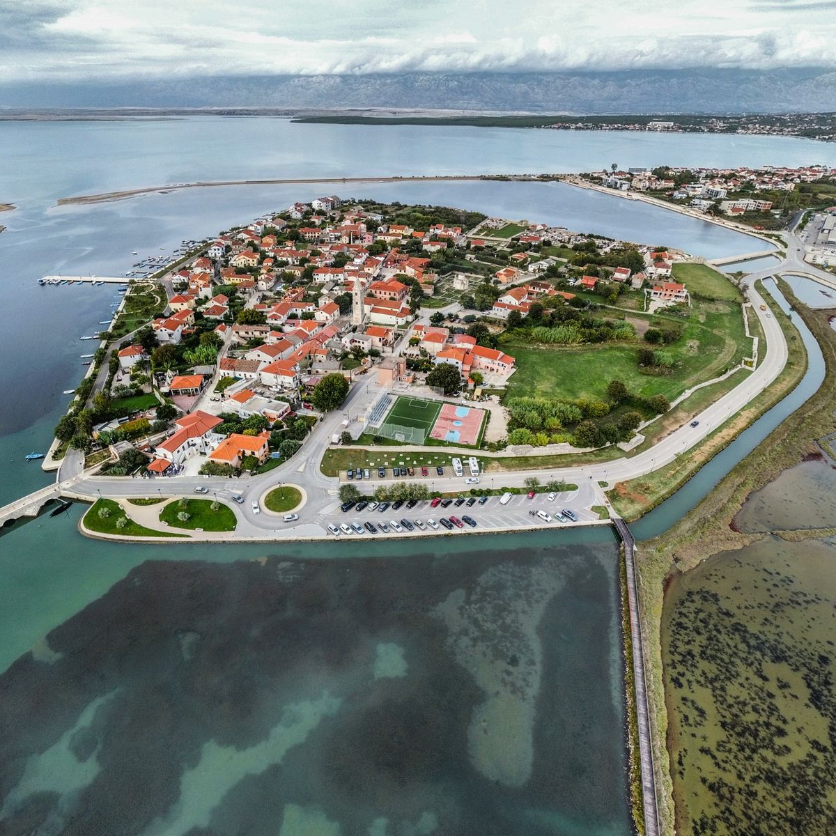 Vue aérienne d'une ville historique cernée par l'eau, illustrant un méandre resserré à couper