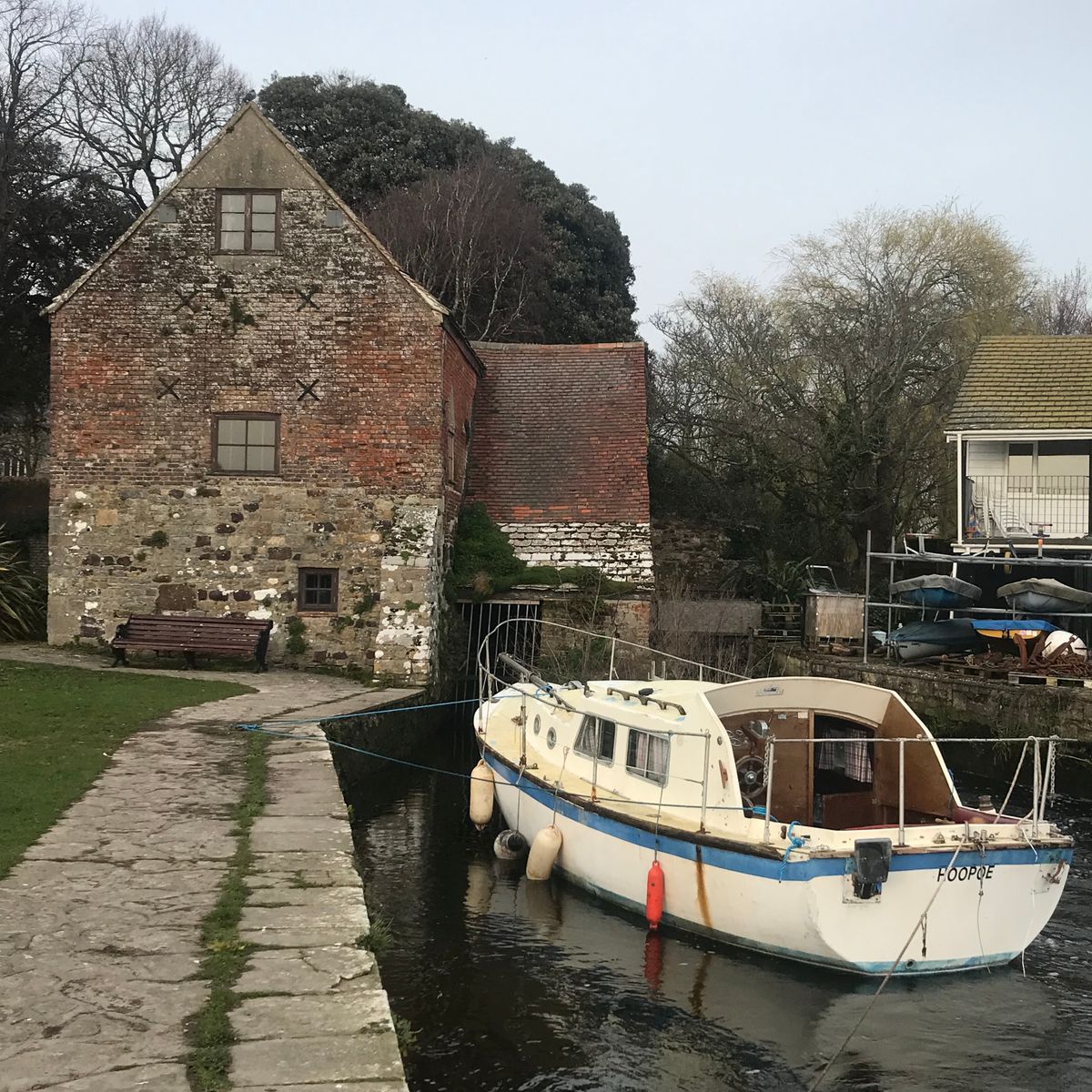 Petit bateau amarré le long d'un canal bordé d'un bâtiment historique en briques