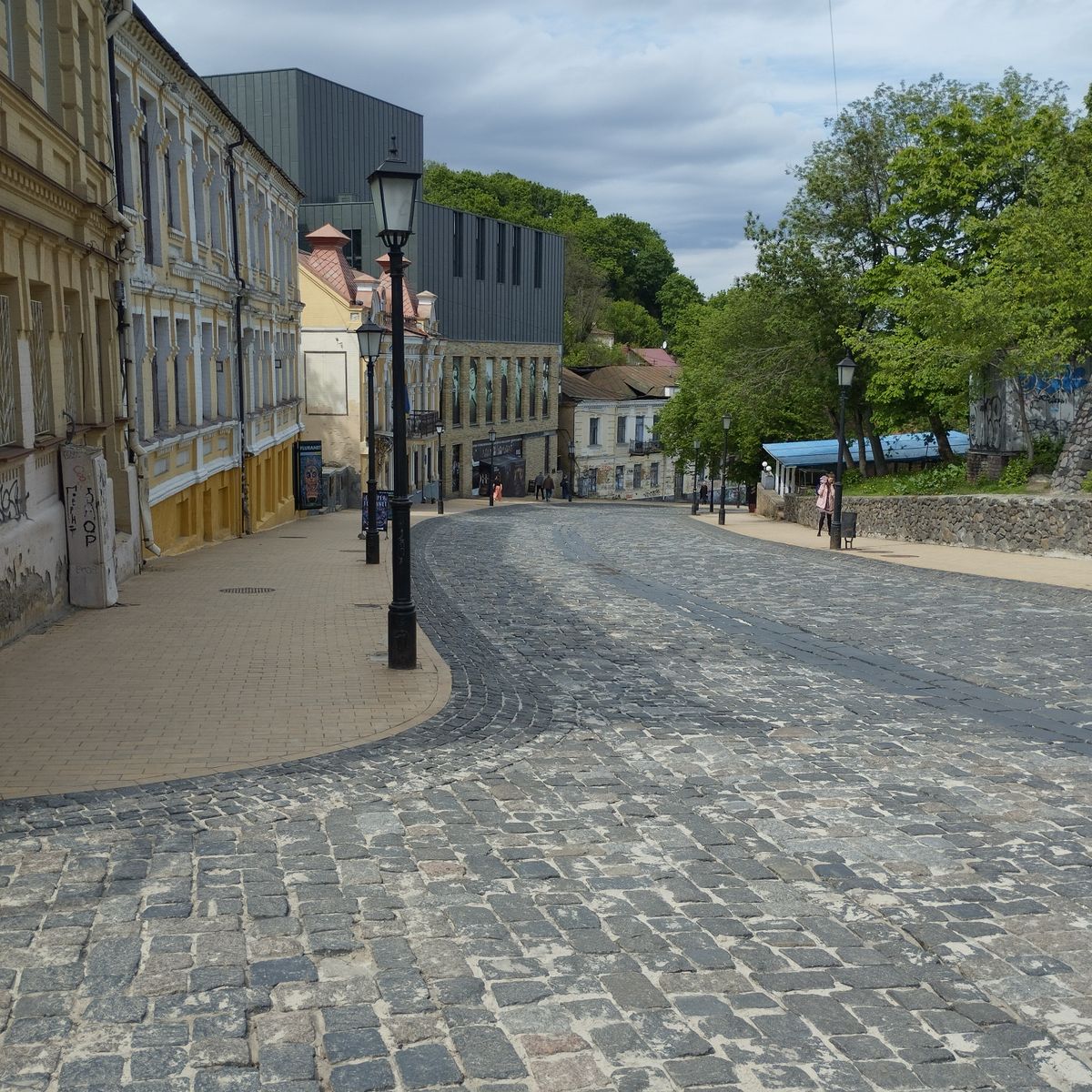 Rue pavée en pente bordée d'immeubles anciens et de réverbères dans un centre historique